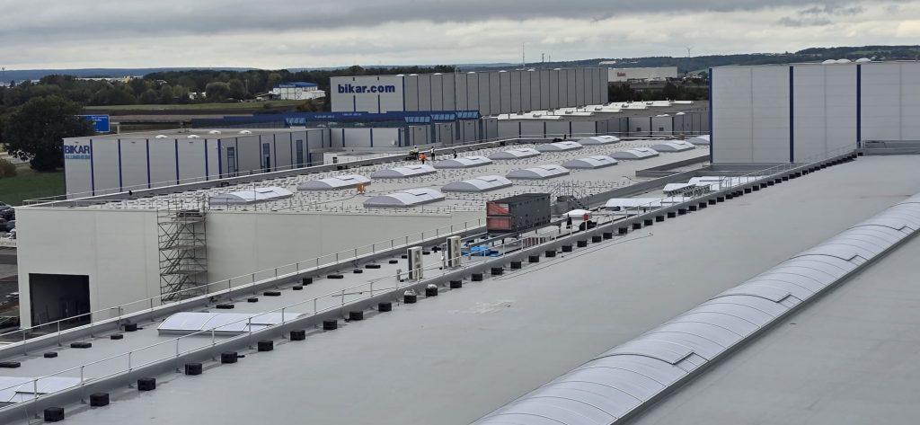 Ein großer Fabrikkomplex mit mehreren weißen Dächern und einem markanten zentralen Gebäude.