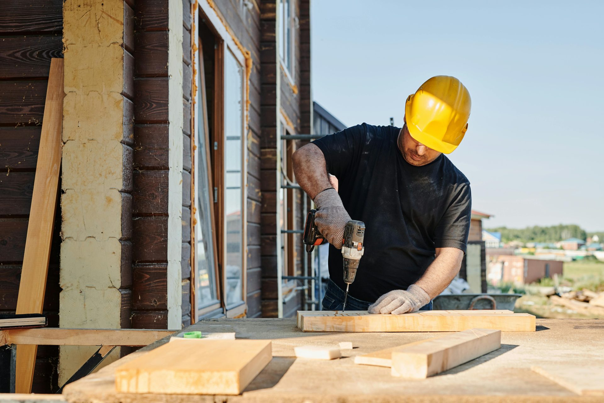Ein Bauarbeiter benutzt tagsüber im Freien auf einer Baustelle eine Bohrmaschine.