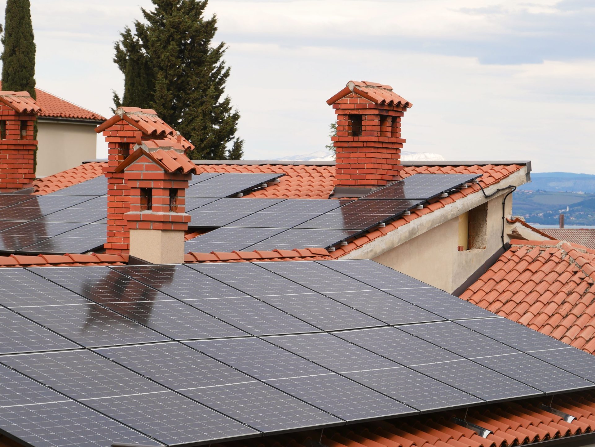 Solarmodule auf Ziegeldächern von Häusern mit Schornsteinen, die saubere Energie gewinnen.